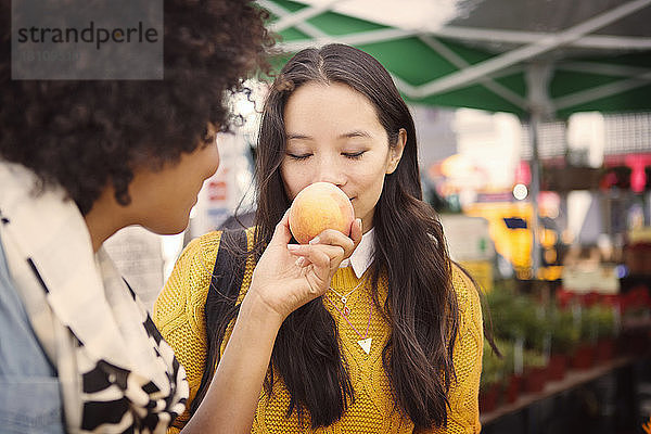 Frau riecht Obst  das ein Freund auf dem Markt hält