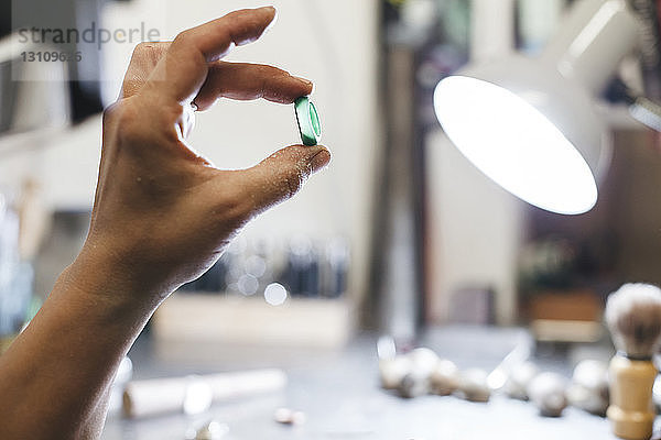 Geschnittene Hand einer Handwerkerin  die einen Ring in der Werkstatt hält