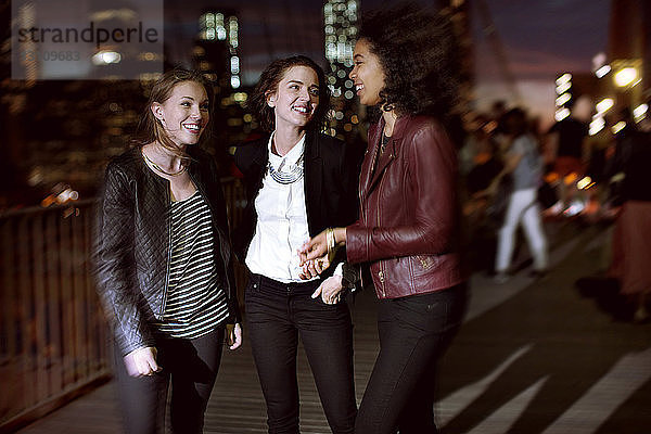 Glückliche Freunde unterhalten sich  während sie nachts auf der Straße stehen