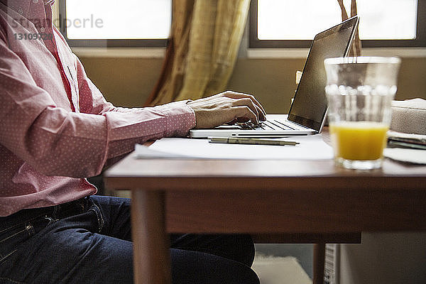 Seitenansicht eines Mannes mit Laptop am Tisch