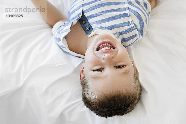 Portrait eines fröhlichen Jungen auf dem Bett liegend