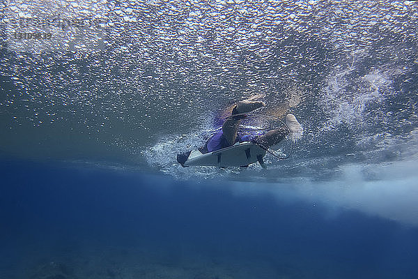 Niedriger Teil des Menschen surft unter Wasser im Meer auf den Malediven