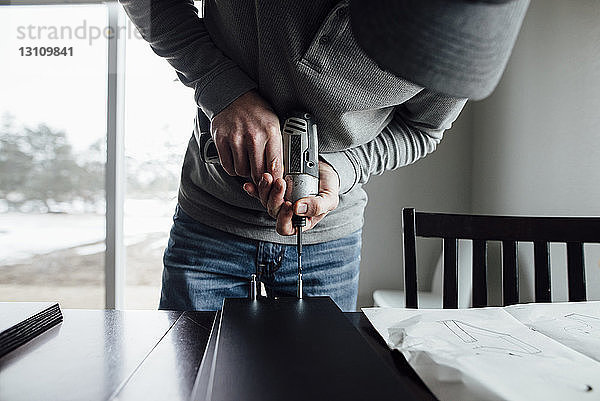 Mann bohrt zu Hause auf dem Tisch