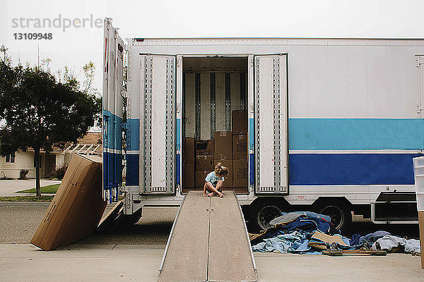 Mädchen sitzt auf der Planke eines Lastwagens