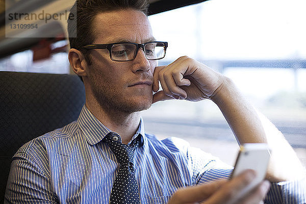 Geschäftsmann benutzt Smartphone während der Zugfahrt