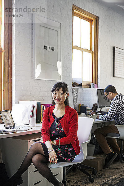 Porträt einer lächelnden Geschäftsfrau  die im Büro sitzt
