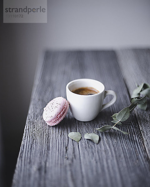 Nahaufnahme von rosa Makrone und Kaffeetasse auf Holztisch