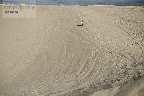 Fernansicht eines Jungen  der am Strand auf Sand steht