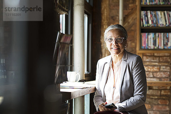 Porträt einer lächelnden Frau beim Kaffeetrinken in einem Café