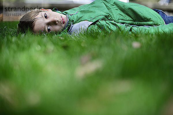 Porträt eines selbstbewussten Jungen auf einem Grasfeld liegend