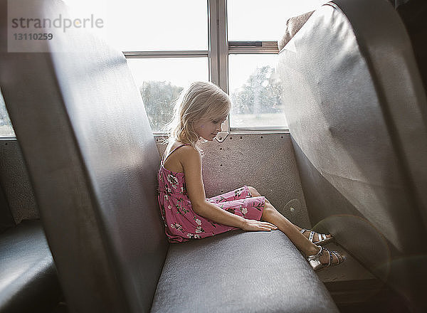 Seitenansicht eines am Fenster sitzenden Mädchens im Bus