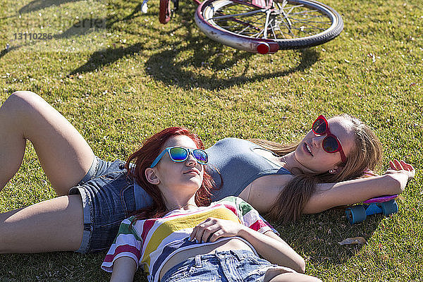 Freundinnen entspannen sich  während sie auf einem Grasfeld im Park liegen