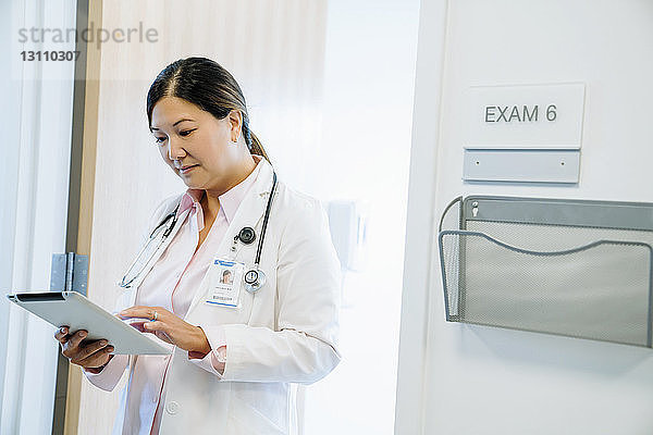 Ärztin  die einen Tablet-Computer benutzt  während sie im Krankenhaus an der Wand steht