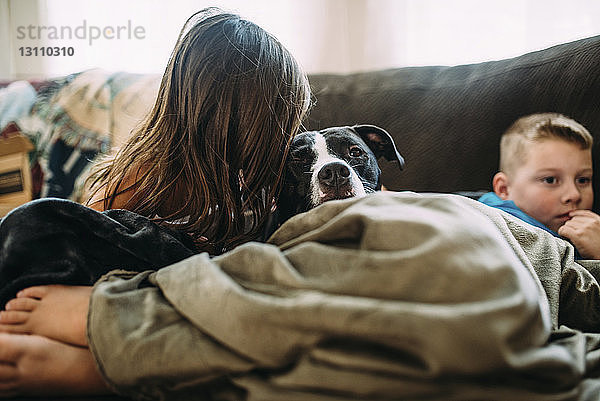 Geschwister mit Hund  die sich zu Hause auf dem Bett ausruhen