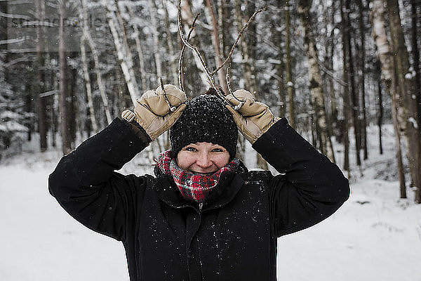 Porträt einer lächelnden Frau  die im Winter im Wald steht und gestikuliert