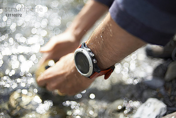 Gekrümmte Hand eines Wanderers mit Armbanduhr am Fluss