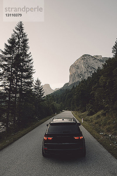 Auto auf der Straße gegen Berg und klaren Himmel in der Dämmerung