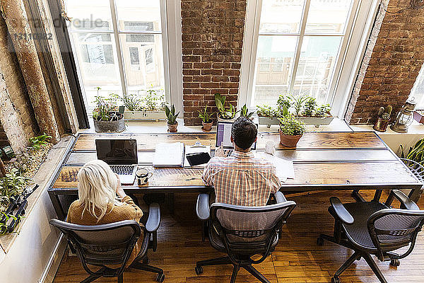 Hochwinkelansicht von männlichen und weiblichen Kollegen  die Laptops am Schreibtisch im Büro benutzen