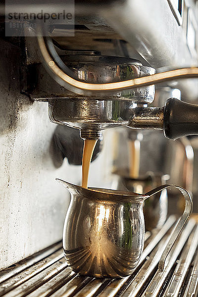 Espressomaschine gießt im Café Kaffee in Krüge