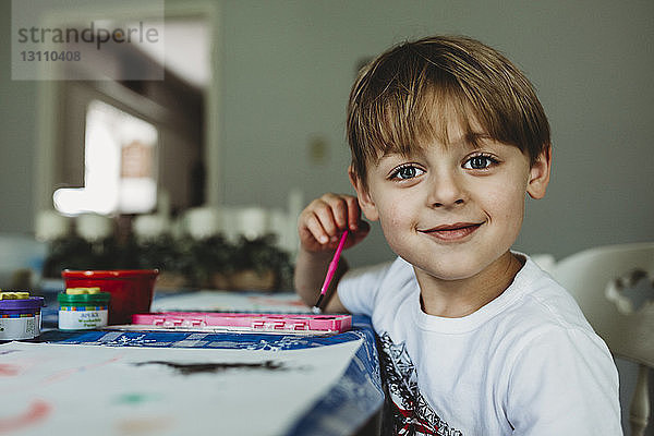 Porträt eines selbstbewussten Jungen  der zu Hause auf dem Tisch malt