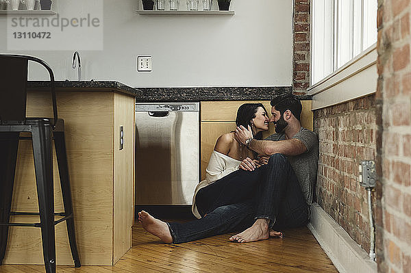Paarromantik  das zu Hause in der Küche an der Wand sitzt
