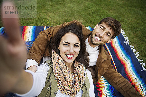 Porträt eines glücklichen Paares auf einer Decke liegend im Park