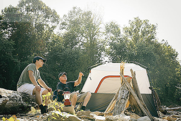 Freunde unterhalten sich  während sie auf dem Campingplatz sitzen