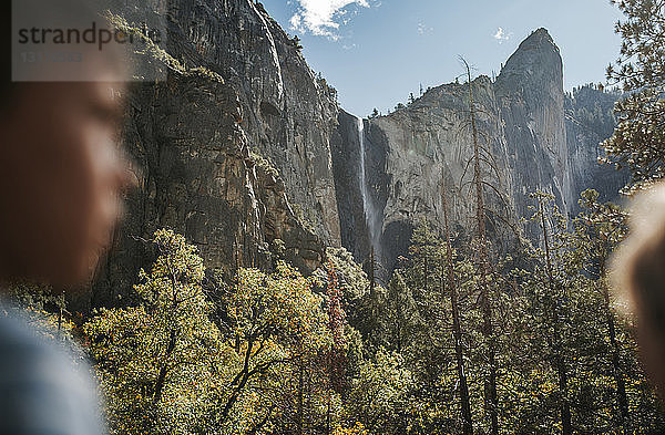 Niedrigwinkel-Szenenansicht eines Wasserfalls mit einem Jungen im Vordergrund im Yosemite National Park