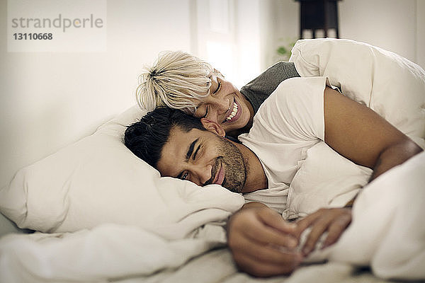 Glückliches junges Paar liegt zu Hause auf dem Bett