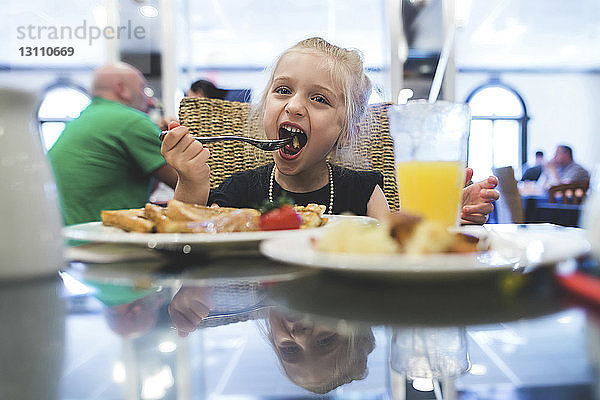 Verspieltes Mädchen beim Essen im Restaurant