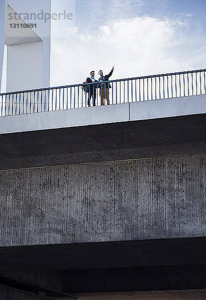 Niedrigwinkelansicht von Männern  die auf einer Brücke in der Stadt gegen den Himmel stehen
