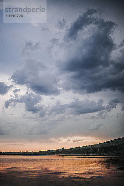 Landschaftliche Ansicht des Flusses vor stürmischen Wolken bei Sonnenuntergang
