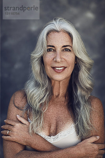 Porträt einer glücklichen reifen Frau mit langen grauen Haaren im Freien