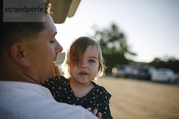 Rückansicht eines Vaters  der eine Tochter trägt