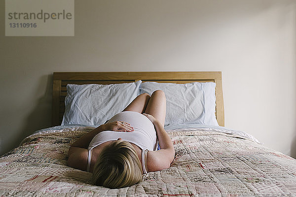 Schwangere Frau entspannt zu Hause im Bett