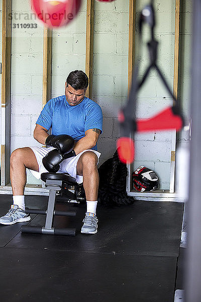 Boxer mit Boxhandschuhen beim Sitzen in der Turnhalle