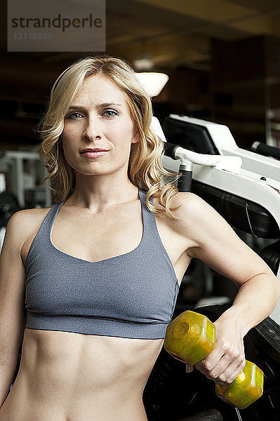 Porträt einer Frau beim Heben einer Hantel im Fitnessstudio