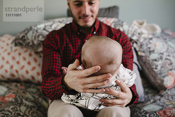 Lächelnder Vater mit Tochter zu Hause im Bett sitzend