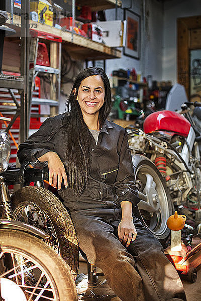 Porträt einer glücklichen Mechanikerin  die in der Werkstatt sitzt