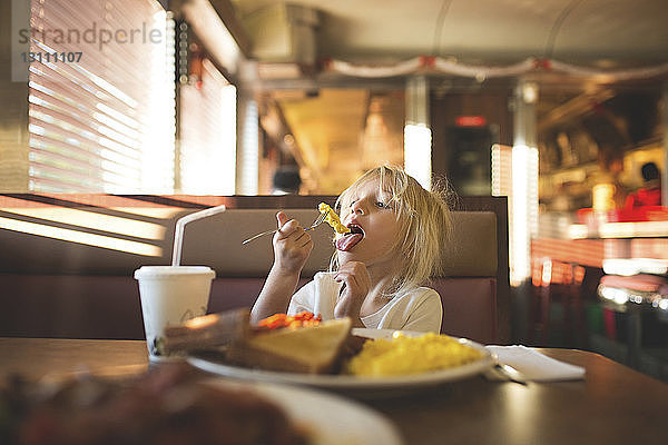 Mädchen isst Essen  während sie im Restaurant sitzt