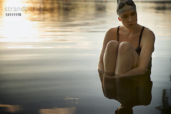 Traurige Schwimmerin auf See sitzend