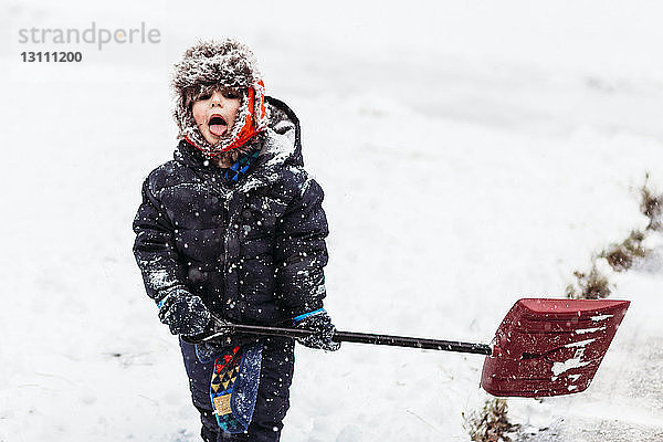 Bildnis eines Jungen  der eine Schaufel hält  während er auf einem schneebedeckten Feld steht