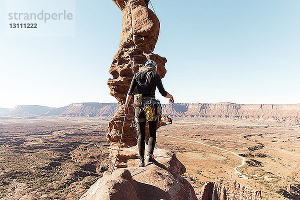 Rückansicht einer Wanderin  die an einem sonnigen Tag auf einer Felsformation bei klarem Himmel wandert