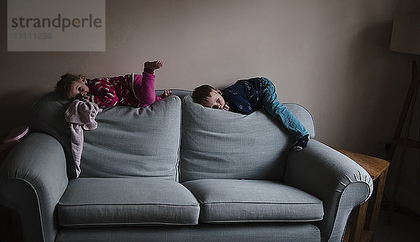 Verspielte Geschwister  die zu Hause auf dem Sofa liegen