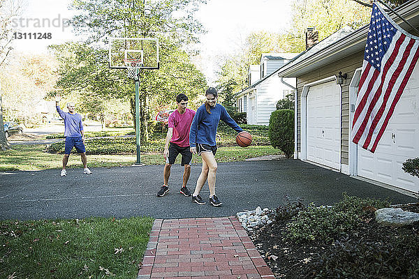 Glückliche Familie spielt Basketball im Hinterhof