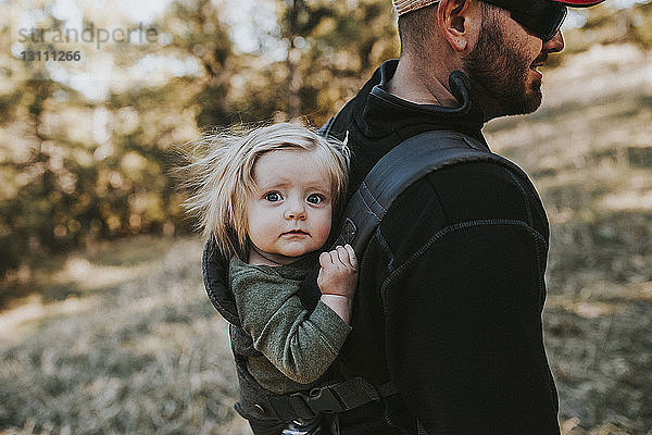 Vater trägt süße Tochter beim Wandern im Wald