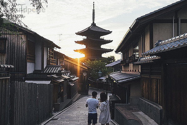 Rückansicht eines Ehepaars  das die Yasaka-Pagode fotografiert  während es auf dem Gehweg steht