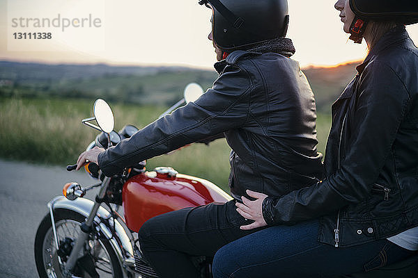 Seitenansicht eines jungen Paares auf Motorrad