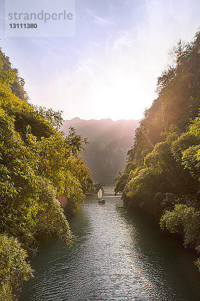 Hochwinkelaufnahme eines Sampans in einem Fluss inmitten von Bergen an einem sonnigen Tag