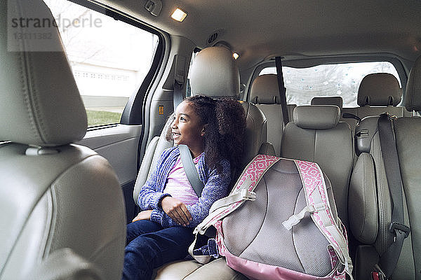Glückliches Mädchen schaut durchs Fenster  während sie im Auto unterwegs ist